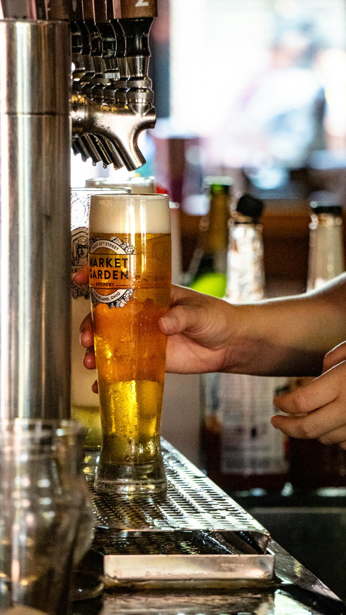 Close-up of draft beer being poured in a busy bar environment. Refreshing and inviting.