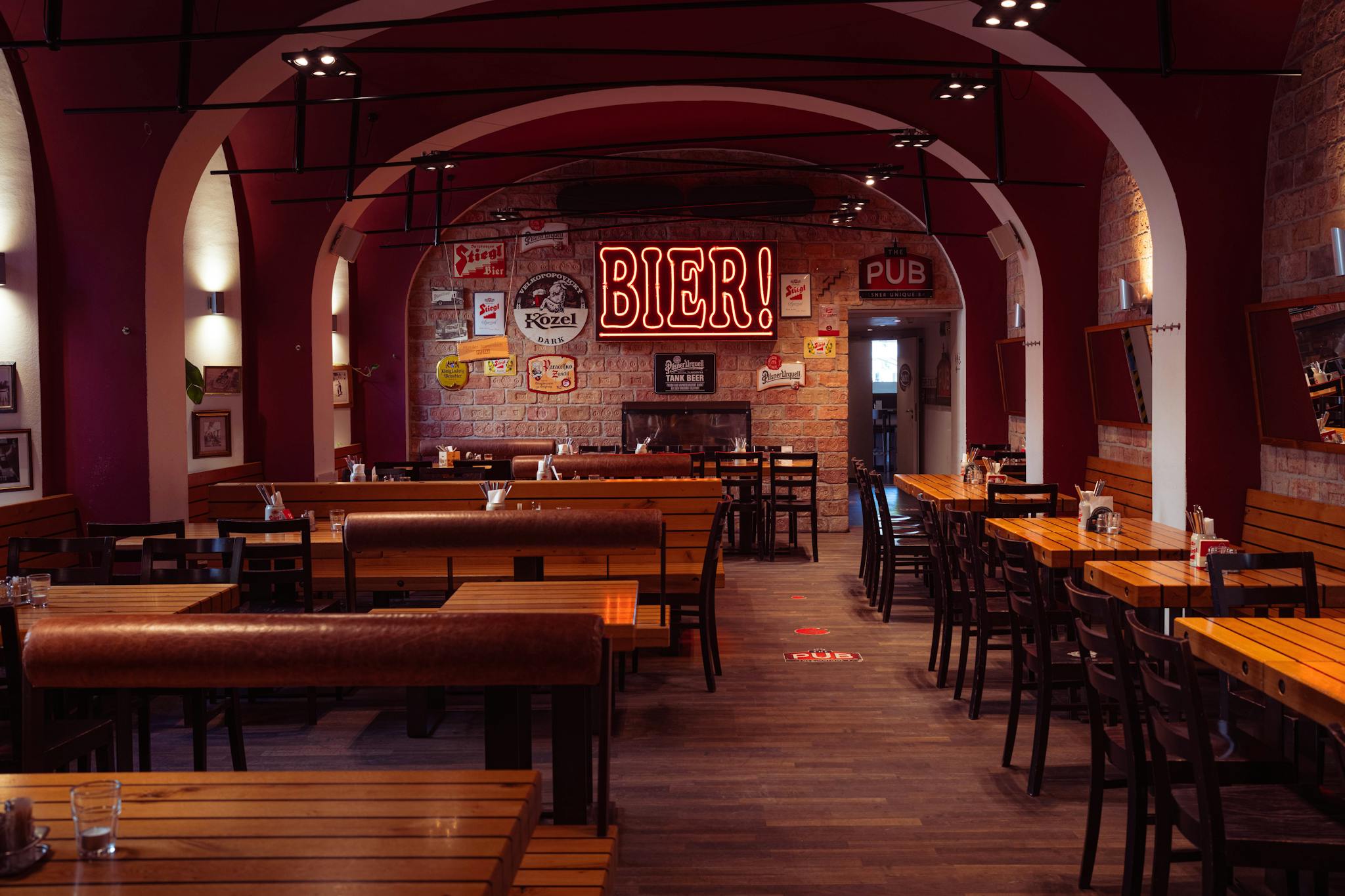 Empty European pub interior showcasing wooden tables, warm lighting, and vintage beer signs, creating a classic inviting ambiance.